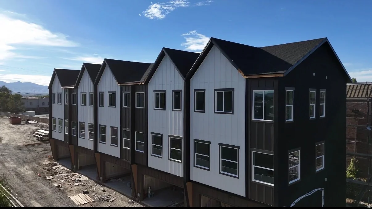 Row of modern townhomes with black and white vertical siding, multiple window configurations, and dark shingled roofs